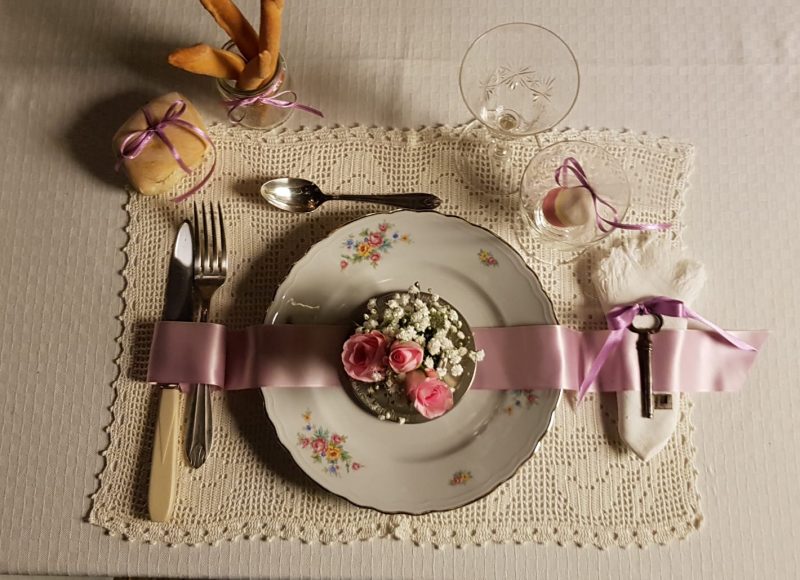 Un tavolo con una tovaglia rosa e un piatto con dei fiori rosa